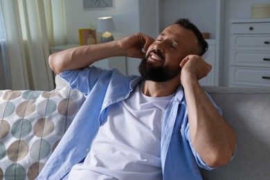 Photo of Harmony. Man listening to music in headphones on sofa at home