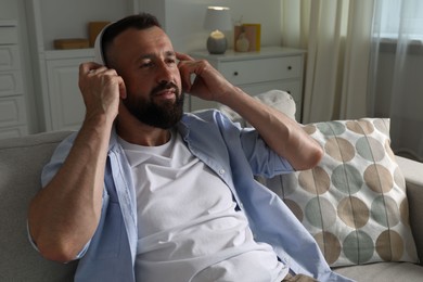 Photo of Harmony. Man listening to music in headphones on sofa at home