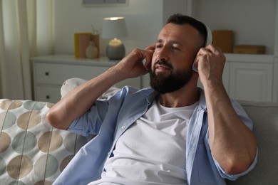 Photo of Harmony. Man listening to music in headphones on sofa at home