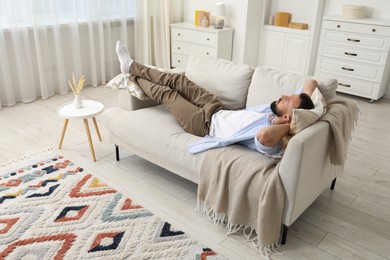 Photo of Harmony. Man relaxing on comfortable sofa at home