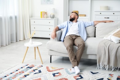 Photo of Harmony. Man relaxing on comfortable sofa at home