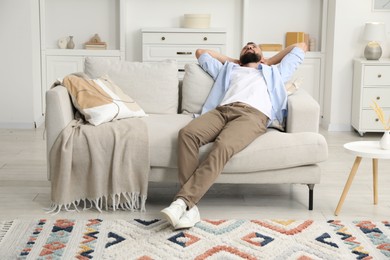 Photo of Harmony. Man relaxing on comfortable sofa at home