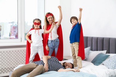 Photo of Parents and children in superhero costumes playing at home
