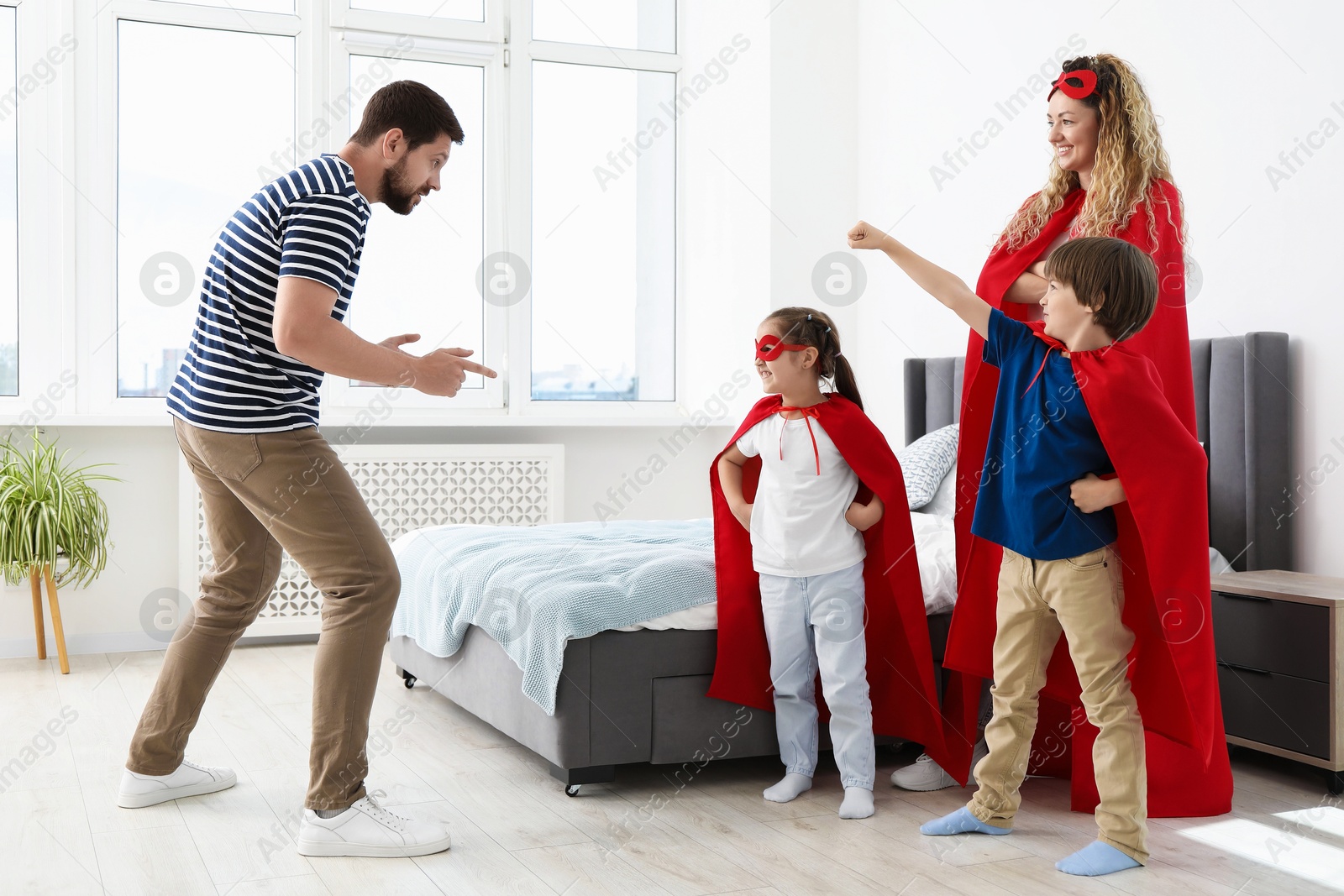 Parents and children in superhero costumes playing at home Photo of Parents and children in superhero costumes playing at home