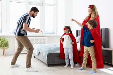 Photo of Parents and children in superhero costumes playing at home