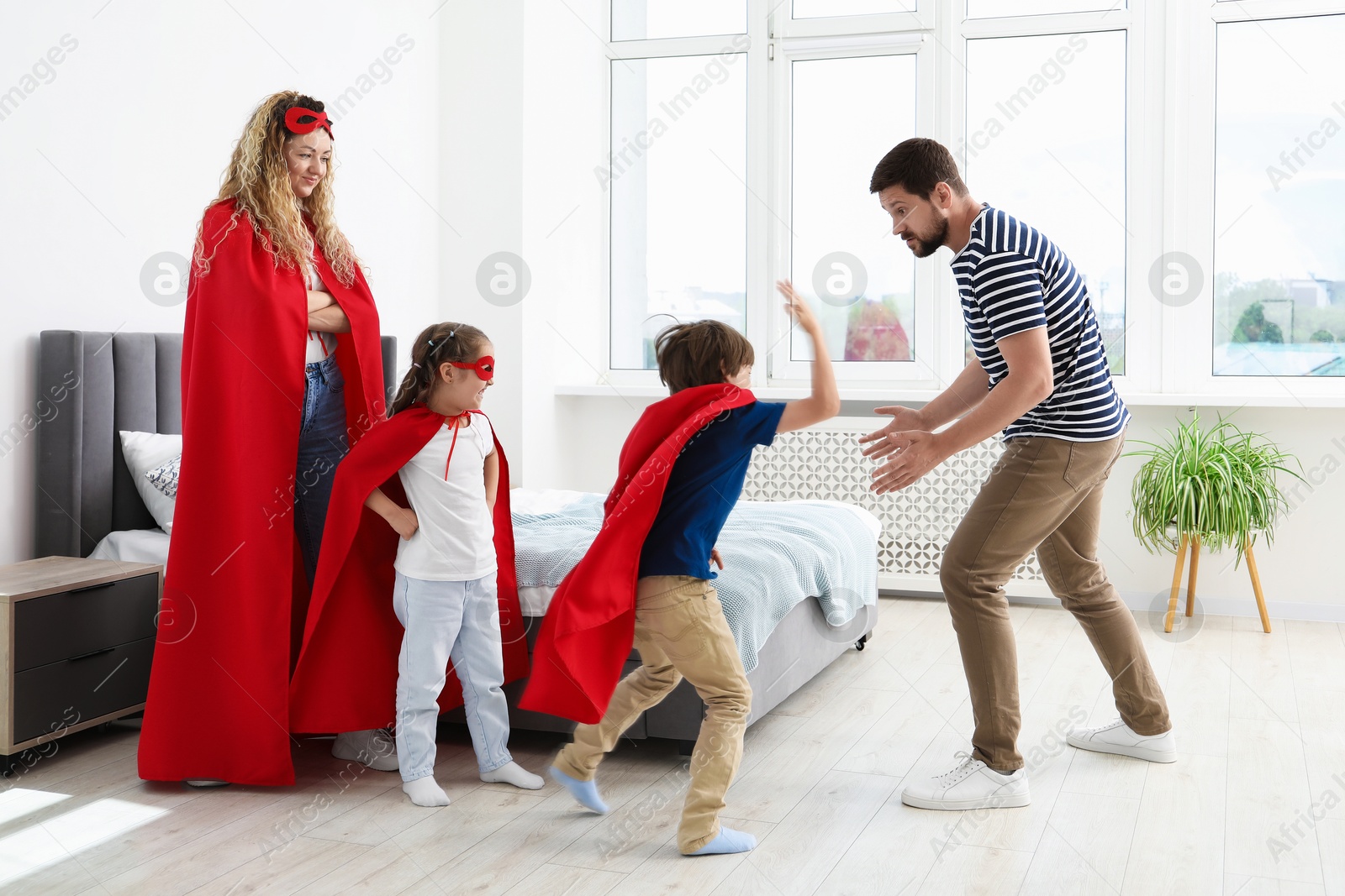 Parents and children in superhero costumes playing at home Photo of Parents and children in superhero costumes playing at home