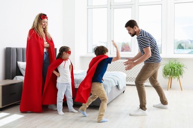Photo of Parents and children in superhero costumes playing at home