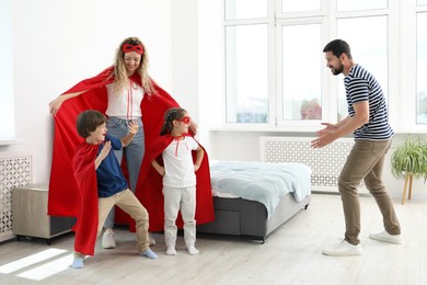 Photo of Parents and children in superhero costumes playing at home