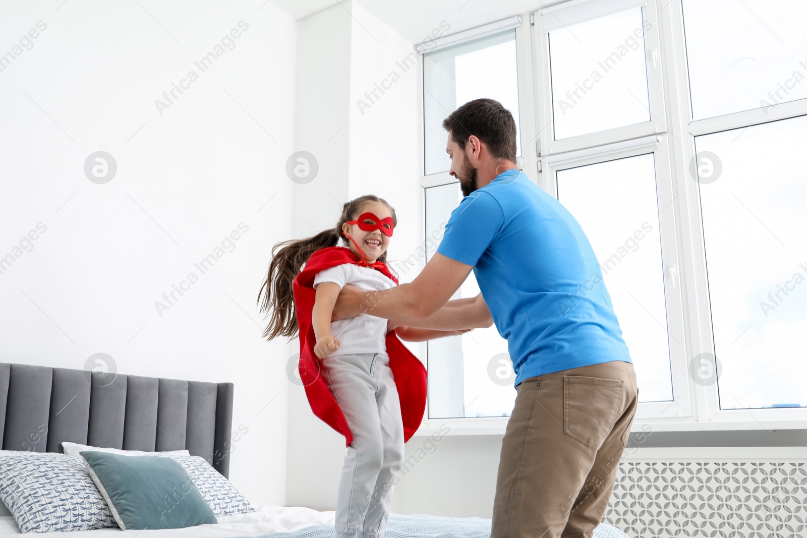 Father and his daughter in superhero costume playing at home Photo of Father and his daughter in superhero costume playing at home