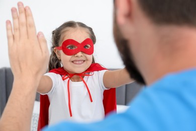 Photo of Father and his daughter in superhero costume playing at home, closeup