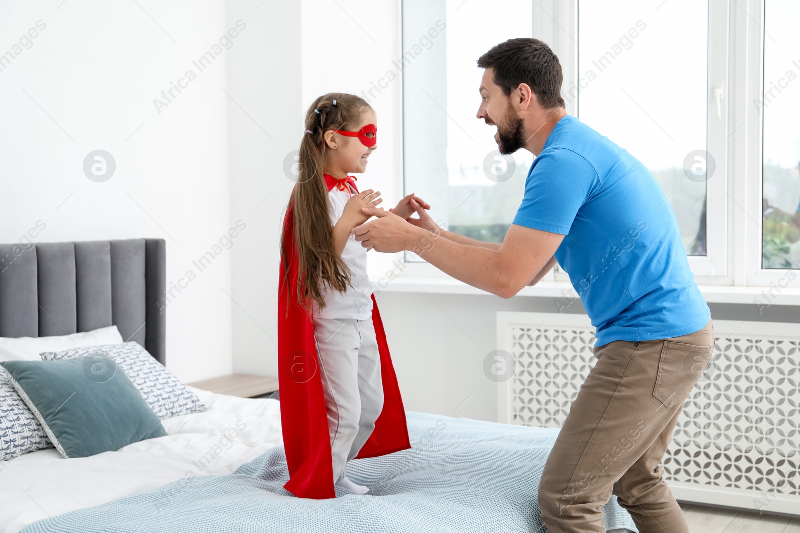 Father and his daughter in superhero costume playing at home Photo of Father and his daughter in superhero costume playing at home