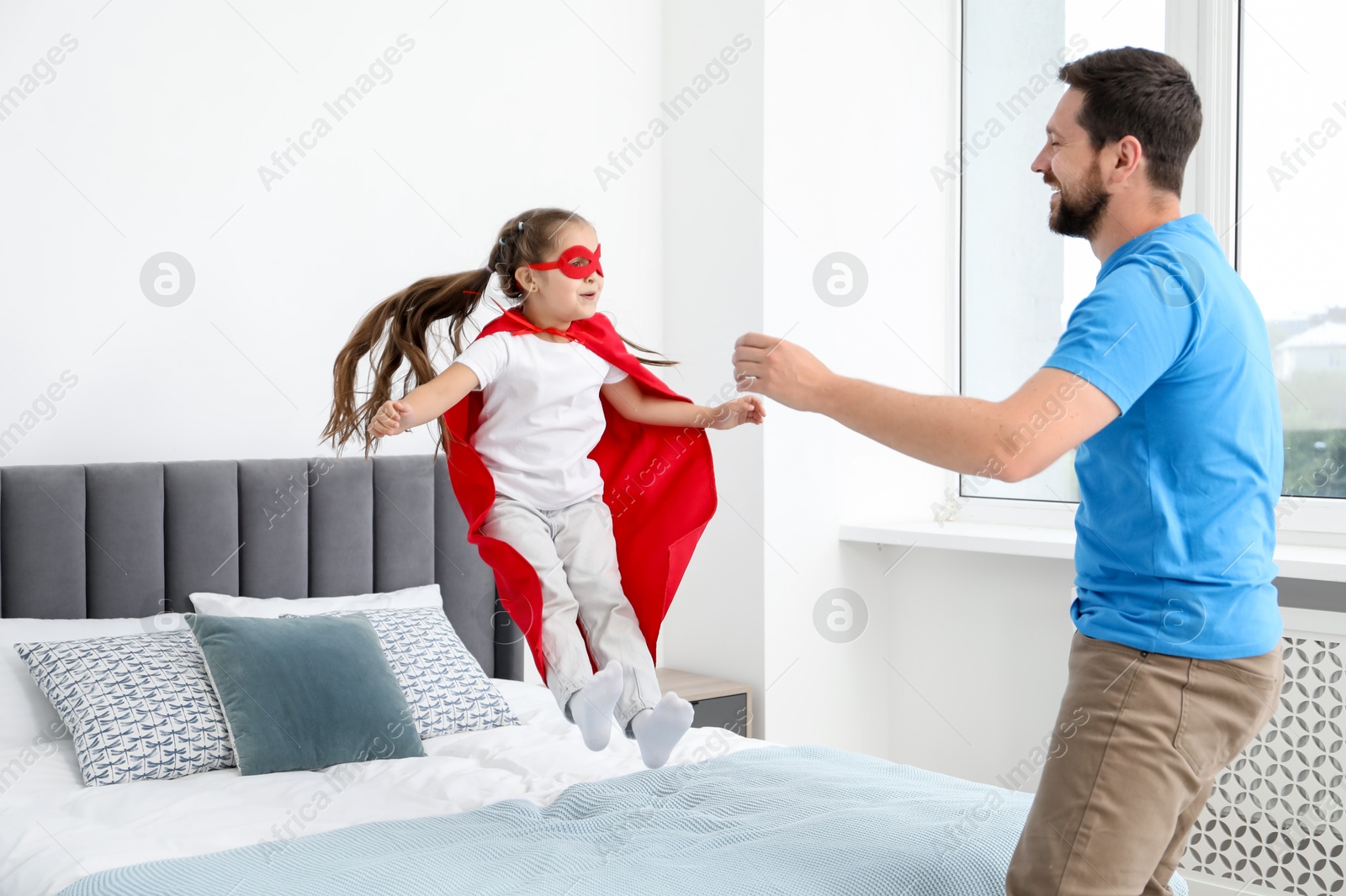 Father and his daughter in superhero costume playing at home Photo of Father and his daughter in superhero costume playing at home