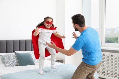 Photo of Father and his daughter in superhero costume playing at home