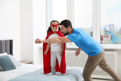 Photo of Father and his daughter in superhero costume playing at home