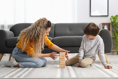 Photo of Mother and her son playing with wooden constructor blocks on floor at home