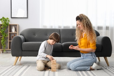Photo of Mother and her son playing with wooden constructor blocks on floor at home