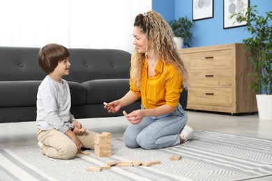 Photo of Mother and her son playing with wooden constructor blocks on floor at home