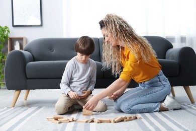 Photo of Mother and her son playing with wooden constructor blocks on floor at home