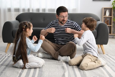 Photo of Children and their father playing on floor at home