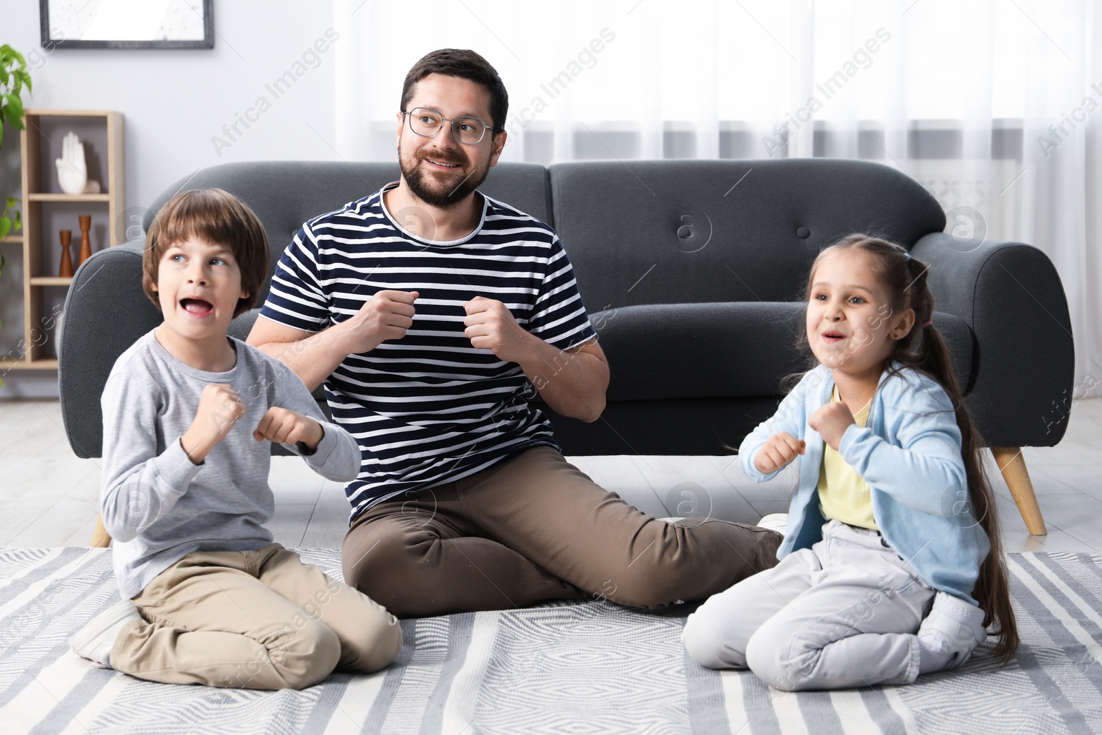Children and their father playing on floor at home Photo of Children and their father playing on floor at home