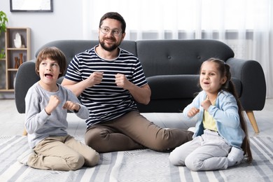 Photo of Children and their father playing on floor at home