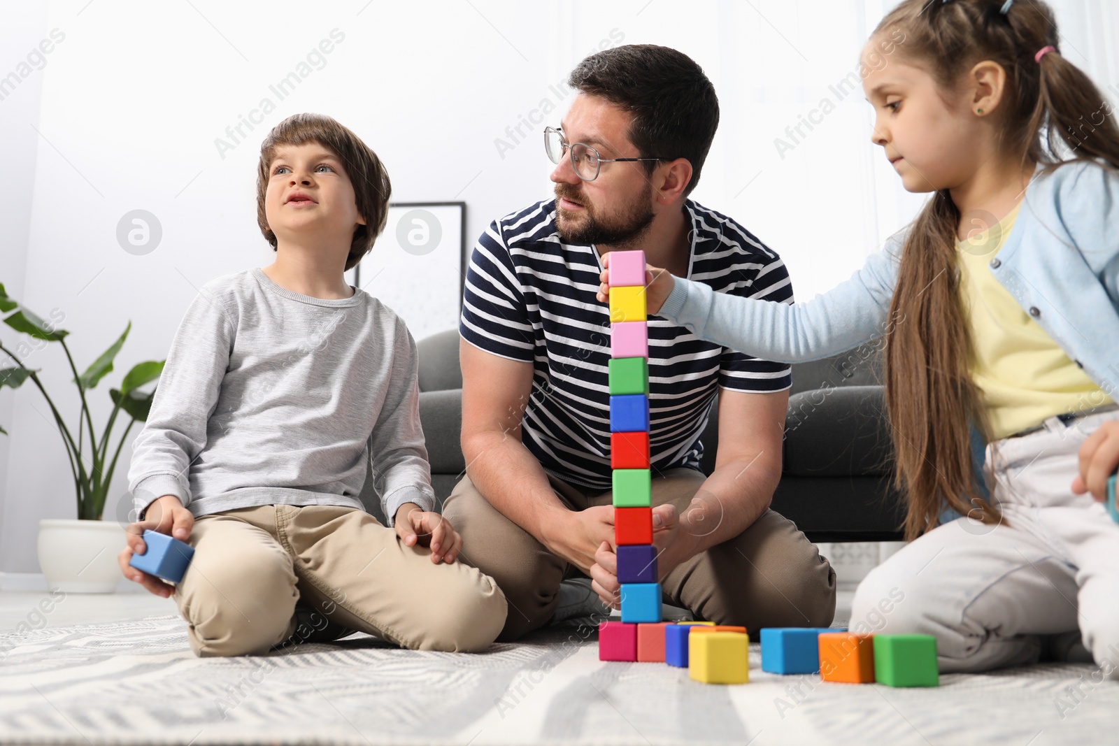 Father and his children playing with colorful cubes on floor at home, low angle view Photo of Father and his children playing with colorful cubes on floor at home, low angle view
