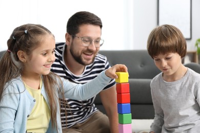 Photo of Father and his children playing with colorful cubes at home, selective focus