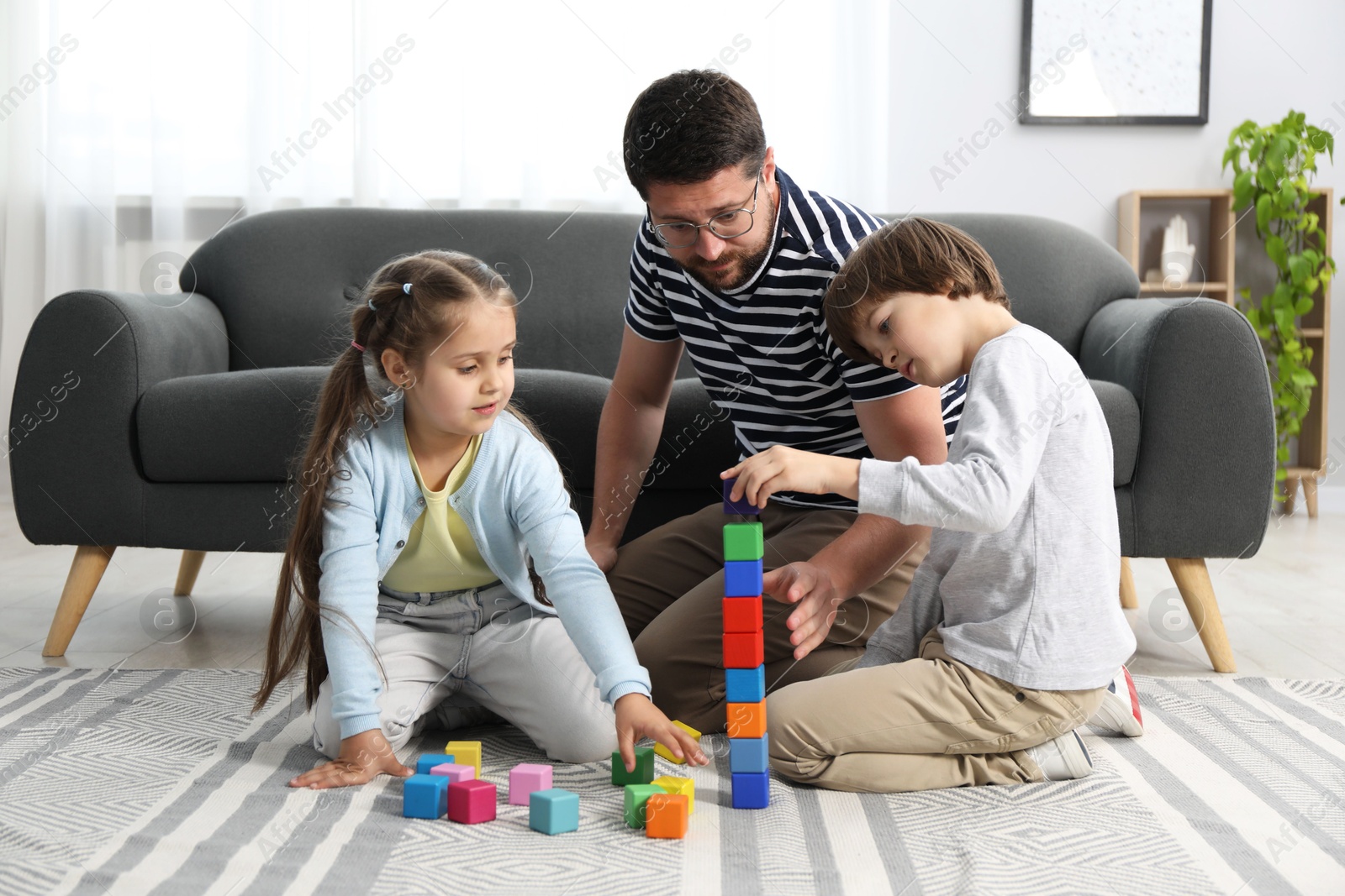 Father and his children playing with colorful cubes on floor at home Photo of Father and his children playing with colorful cubes on floor at home