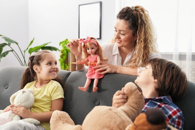 Photo of Children and their mother playing with different toys on sofa at home