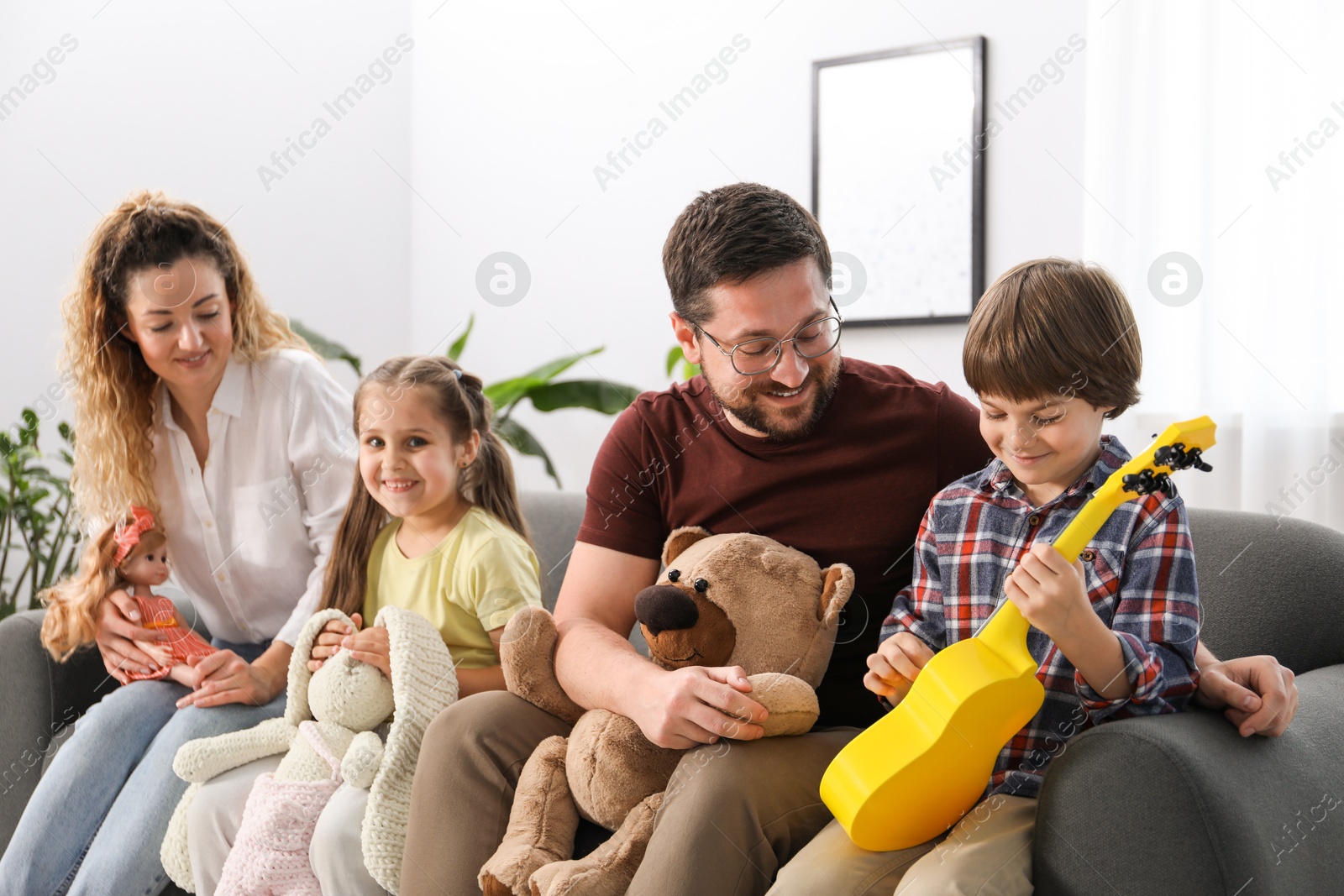 Children and their parents playing with different toys on sofa at home Photo of Children and their parents playing with different toys on sofa at home