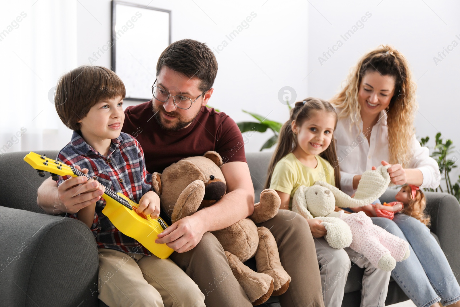 Children and their parents playing with different toys on sofa at home Photo of Children and their parents playing with different toys on sofa at home