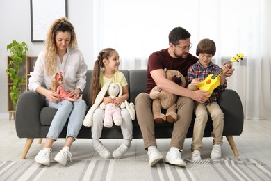 Photo of Children and their parents playing with different toys on sofa at home