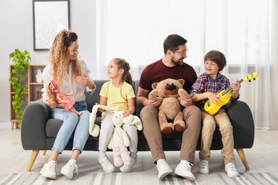 Photo of Children and their parents playing with different toys on sofa at home