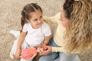 Photo of Mother and her daughter playing with doll on floor at home, above view