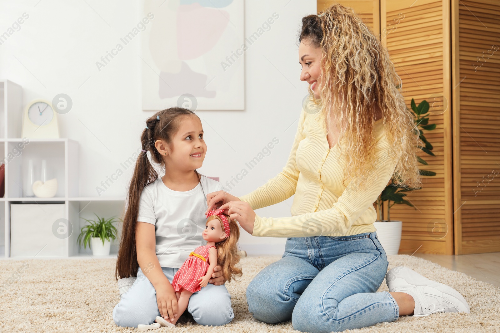 Mother and her daughter playing with doll on floor at home Photo of Mother and her daughter playing with doll on floor at home