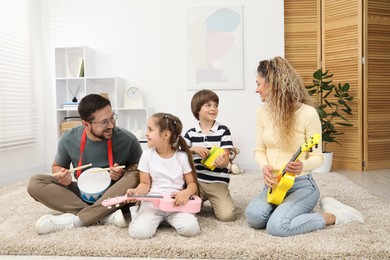 Photo of Parents and their children playing music instruments on floor at home