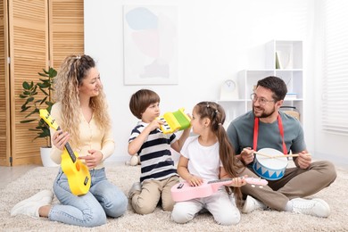 Photo of Parents and their children playing music instruments on floor at home
