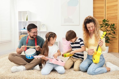 Photo of Parents and their children playing music instruments on floor at home