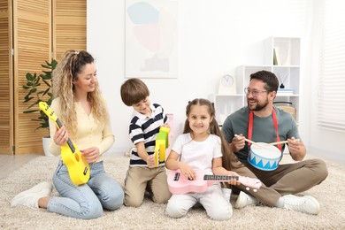 Photo of Parents and their children playing music instruments on floor at home