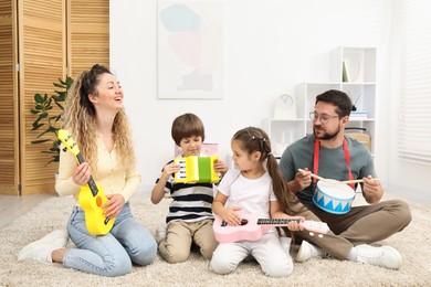 Photo of Parents and their children playing music instruments on floor at home