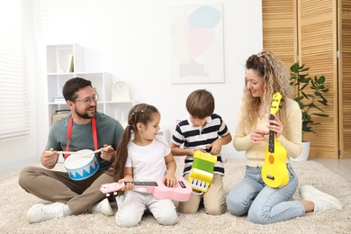 Photo of Parents and their children playing music instruments on floor at home