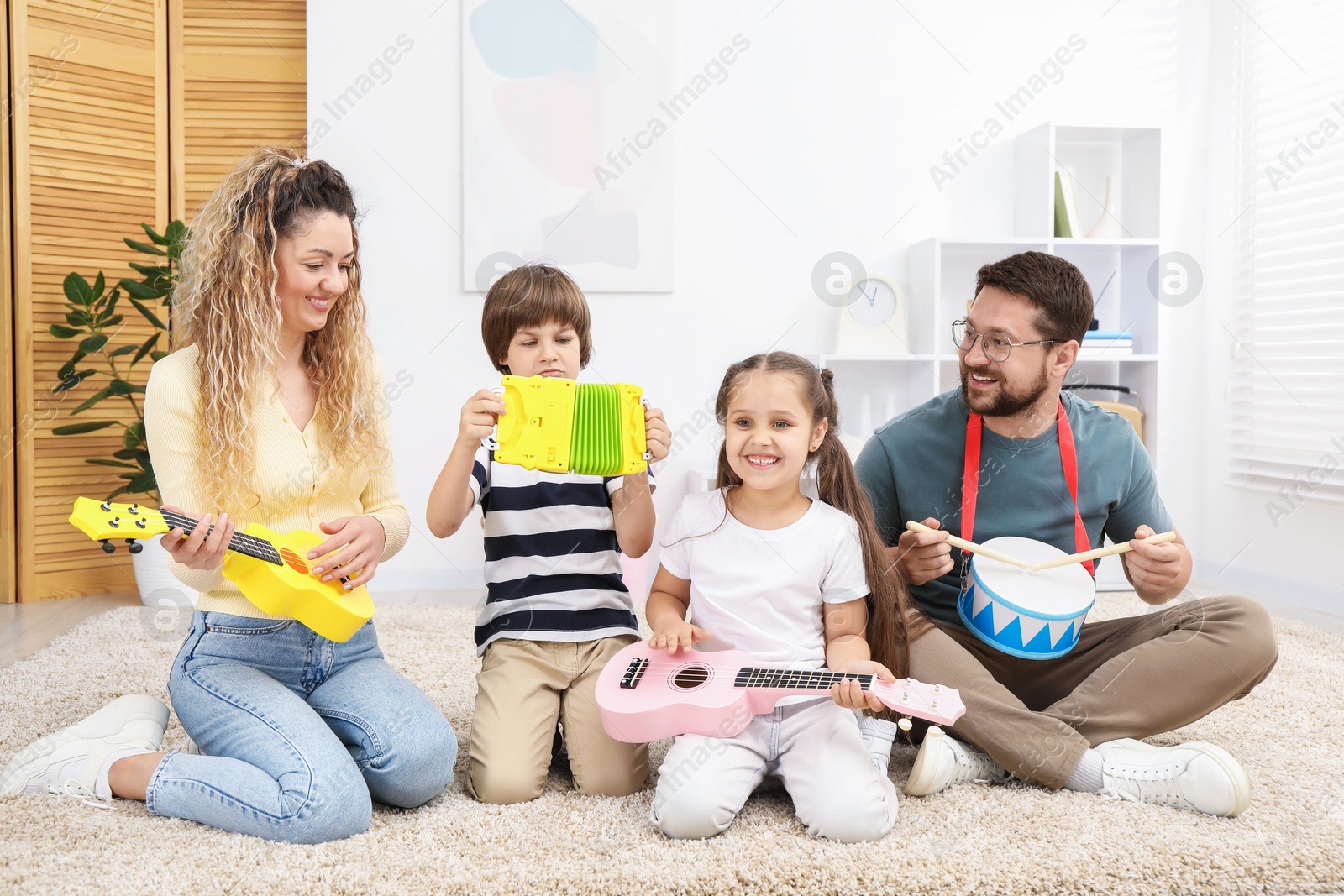 Parents and their children playing music instruments on floor at home Photo of Parents and their children playing music instruments on floor at home