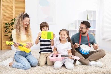 Photo of Parents and their children playing music instruments on floor at home