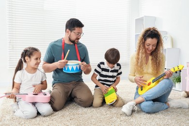 Photo of Parents and their children playing music instruments on floor at home