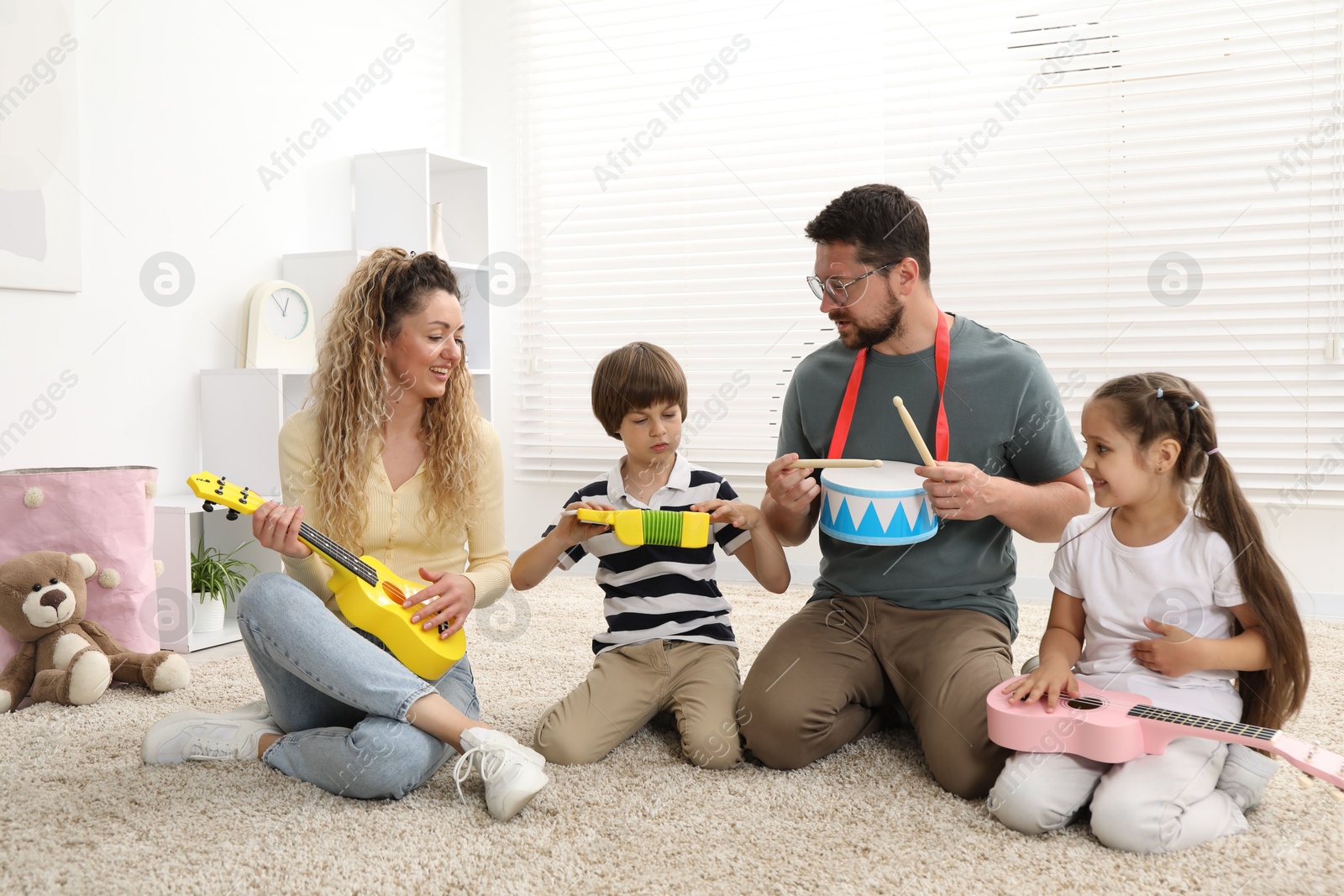 Parents and their children playing music instruments on floor at home Photo of Parents and their children playing music instruments on floor at home