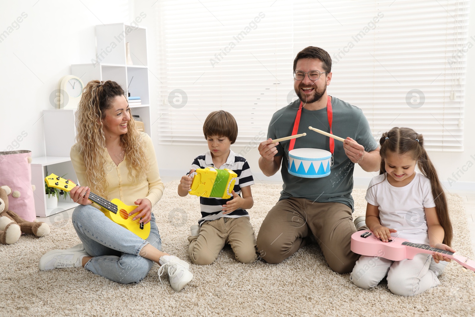 Parents and their children playing music instruments on floor at home Photo of Parents and their children playing music instruments on floor at home
