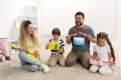 Photo of Parents and their children playing music instruments on floor at home
