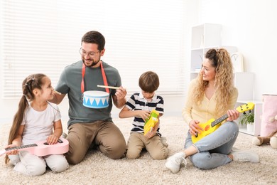Photo of Parents and their children playing music instruments on floor at home