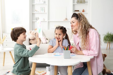 Photo of Mother and her children drawing at white table indoors