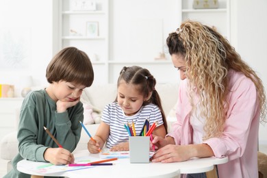 Photo of Mother and her children drawing at white table indoors